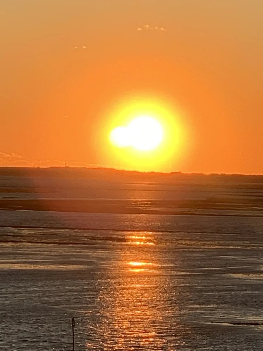 The sun low over the salt marsh, its reflection running the length of the channel below